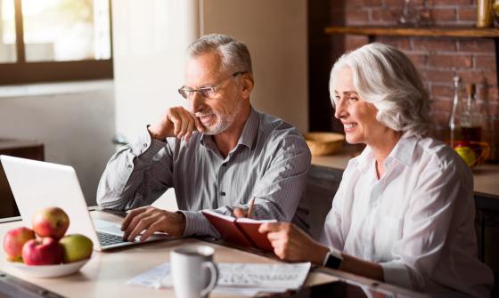 Man and woman use laptop at kitchen table