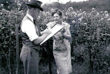 Man with a clipboard talking to a woman in a field