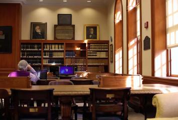 Library with sun through windows, man seated facing away from camera