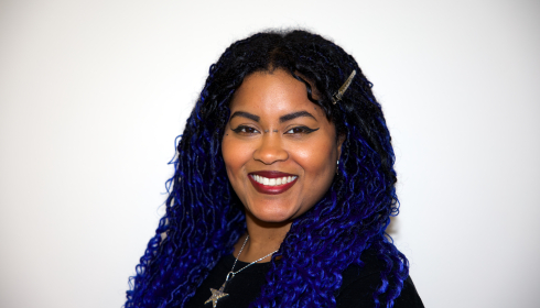 Staff photograph of a woman in the center of the image with an off-white background.