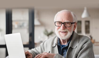 What's New at American Ancestors older man with beard and glasses on laptop