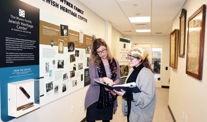 two women standing in a hallway reading archival materials