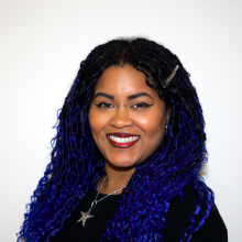 Staff photograph of a woman in the center of the image with an off-white background.