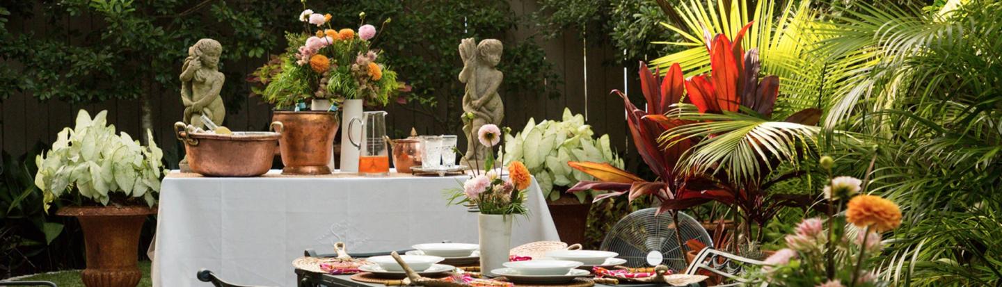 Classical Shindig: Amateur Artistry From Two New Orleans Gentlemen garden party setup with tables, plates, and flowers