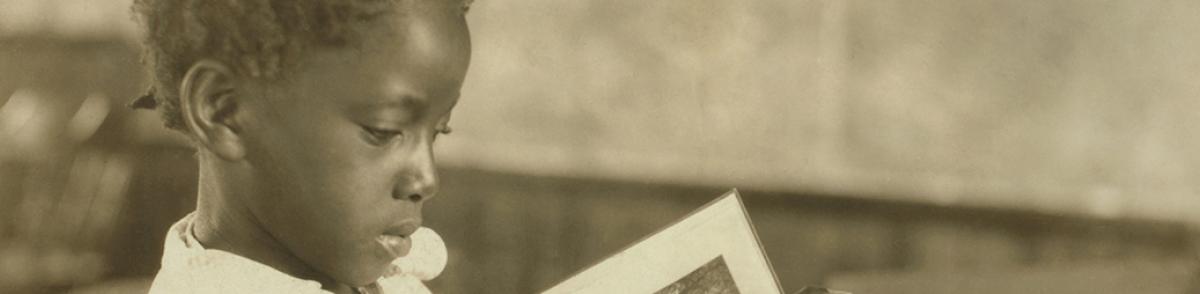 Young girl reading a book in a school room