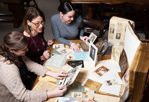 Three people with books and heirlooms at table