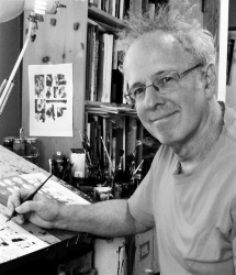 Dan Mazur posing at his drawing desk in black and white with a pen in hand