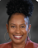 Headshot of Judy Morse, a black woman with black hair put up in a bun. She is wearing a rust red shirt and hoop earrings.