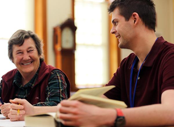 Two researchers smiling over a book