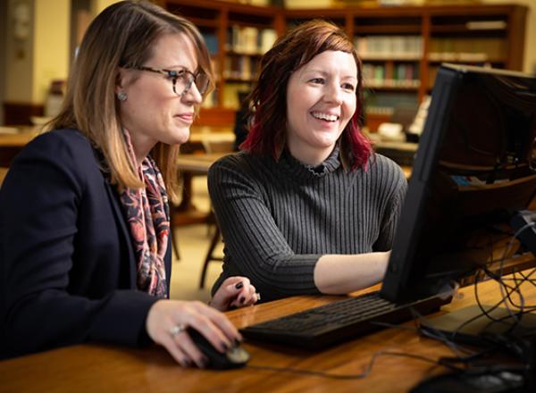 Two researchers look at a computer together