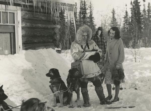 A census-taker arrives at a woman's home by dogsled