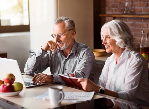 Man and woman use laptop at kitchen table