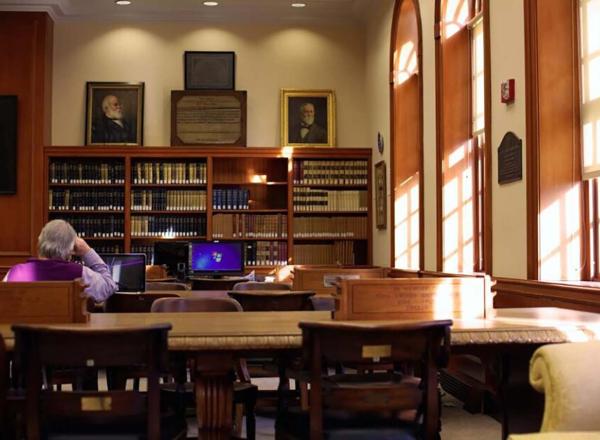 Library with sun through windows, man seated facing away from camera