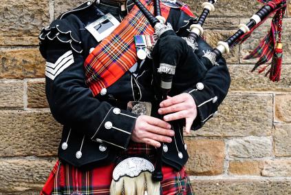 Tracing Tartans: Researching Scottish Clans Scottish bagpiper dressed in traditional red and black tartan dress