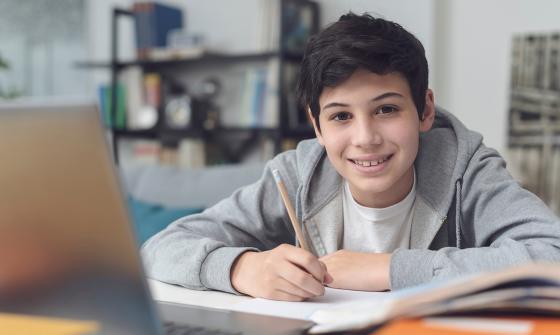 Student writing and smiling