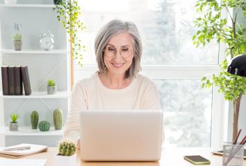 Smiling woman sits at laptop
