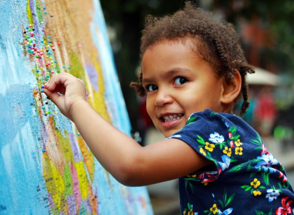 Child putting pin in a map