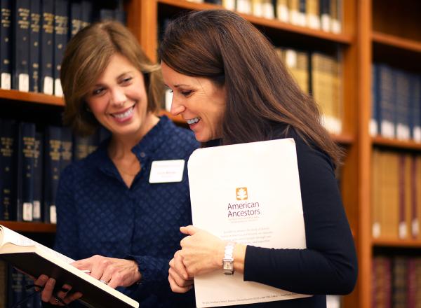 Researcher and client review documents near bookshelves